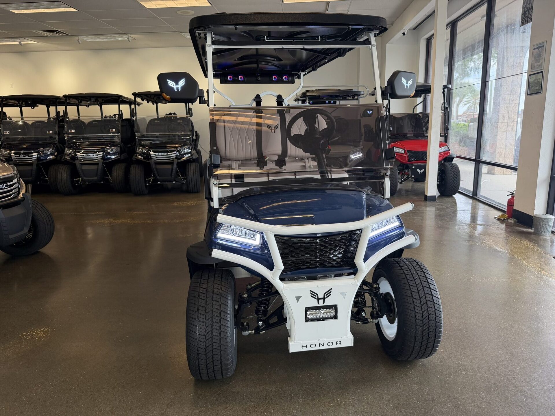 Navy-and-white Honor G1 golf cart with cream tufted leather seats in the showroom