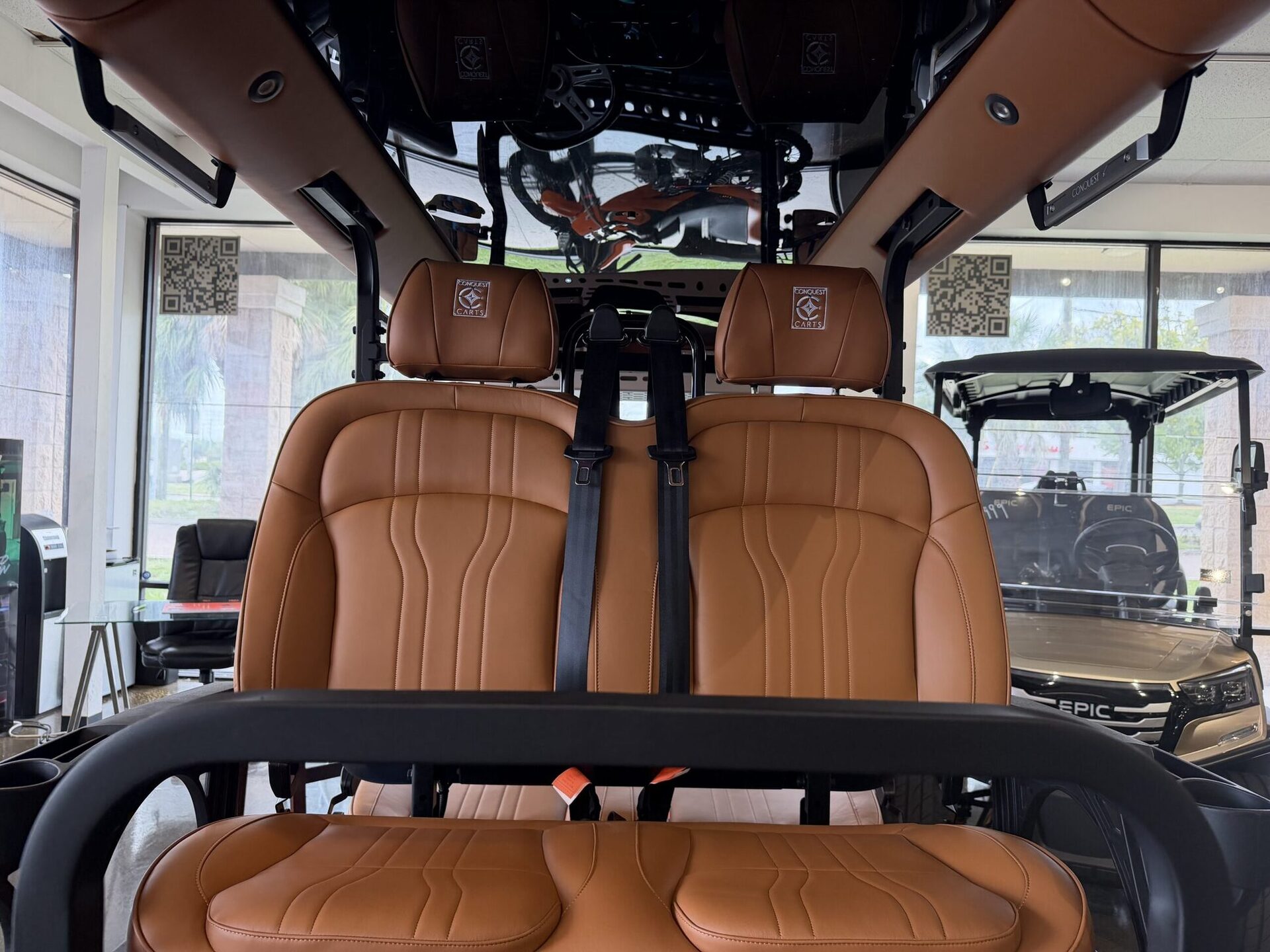 Cognac saddle-leather bucket seats with ICON-branded headrests inside a six-seat golf cart