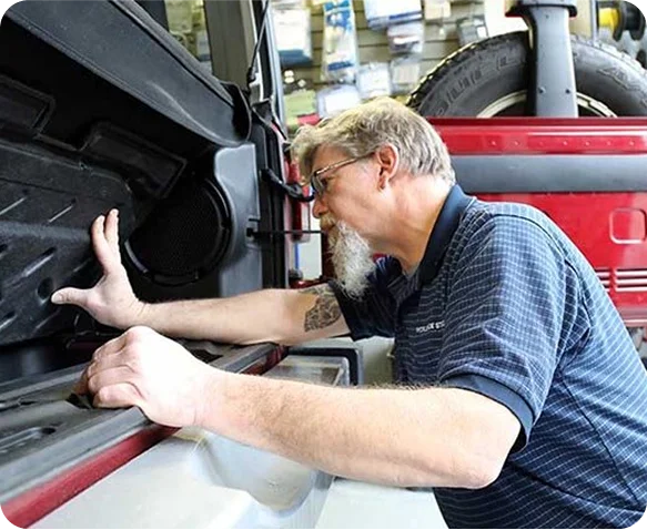 Technician installing a marine speaker into a red golf cart body panel