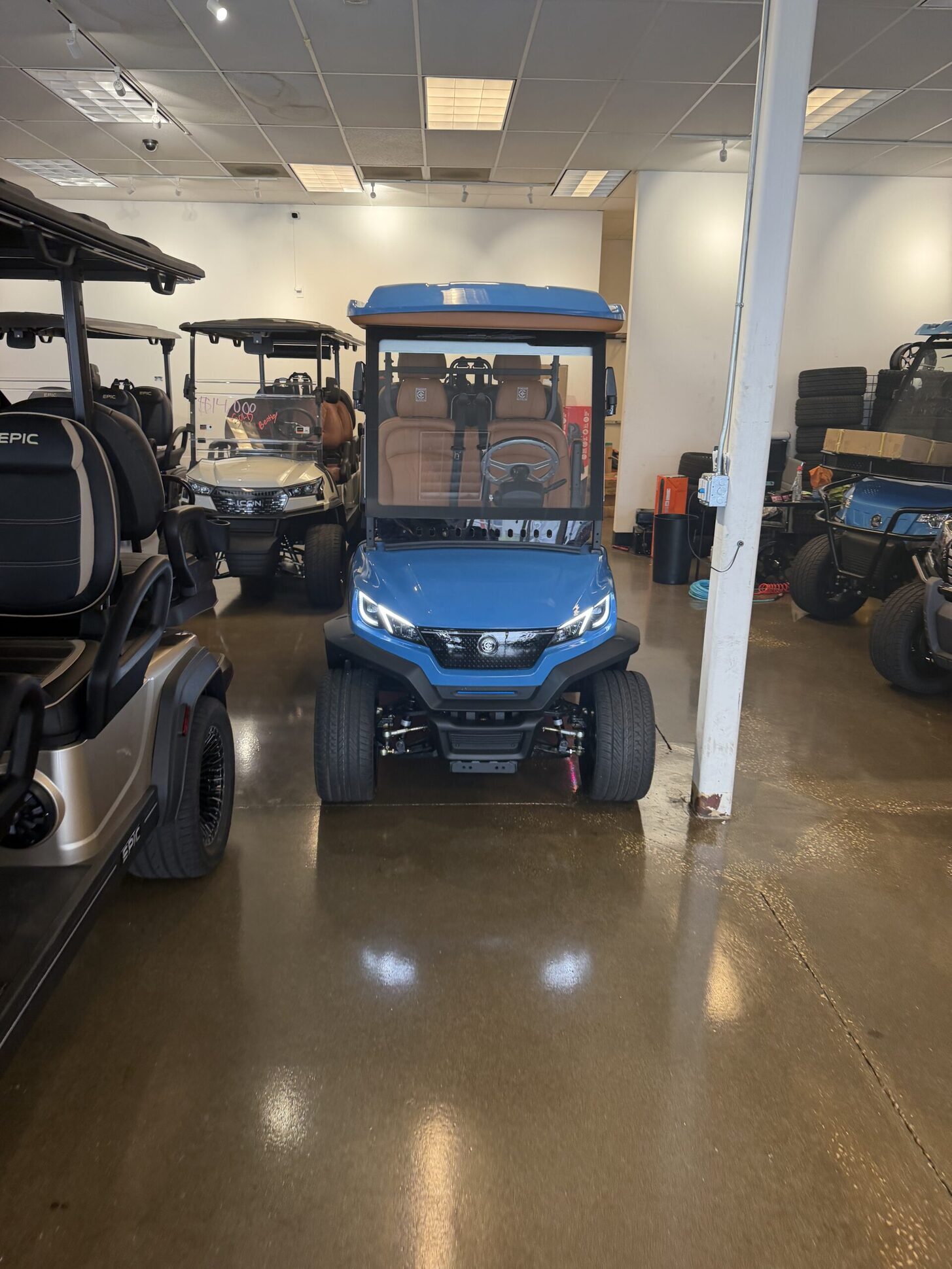 Electric-blue ICON four-passenger golf cart head-on in the Tampa Bay showroom with rows of inventory